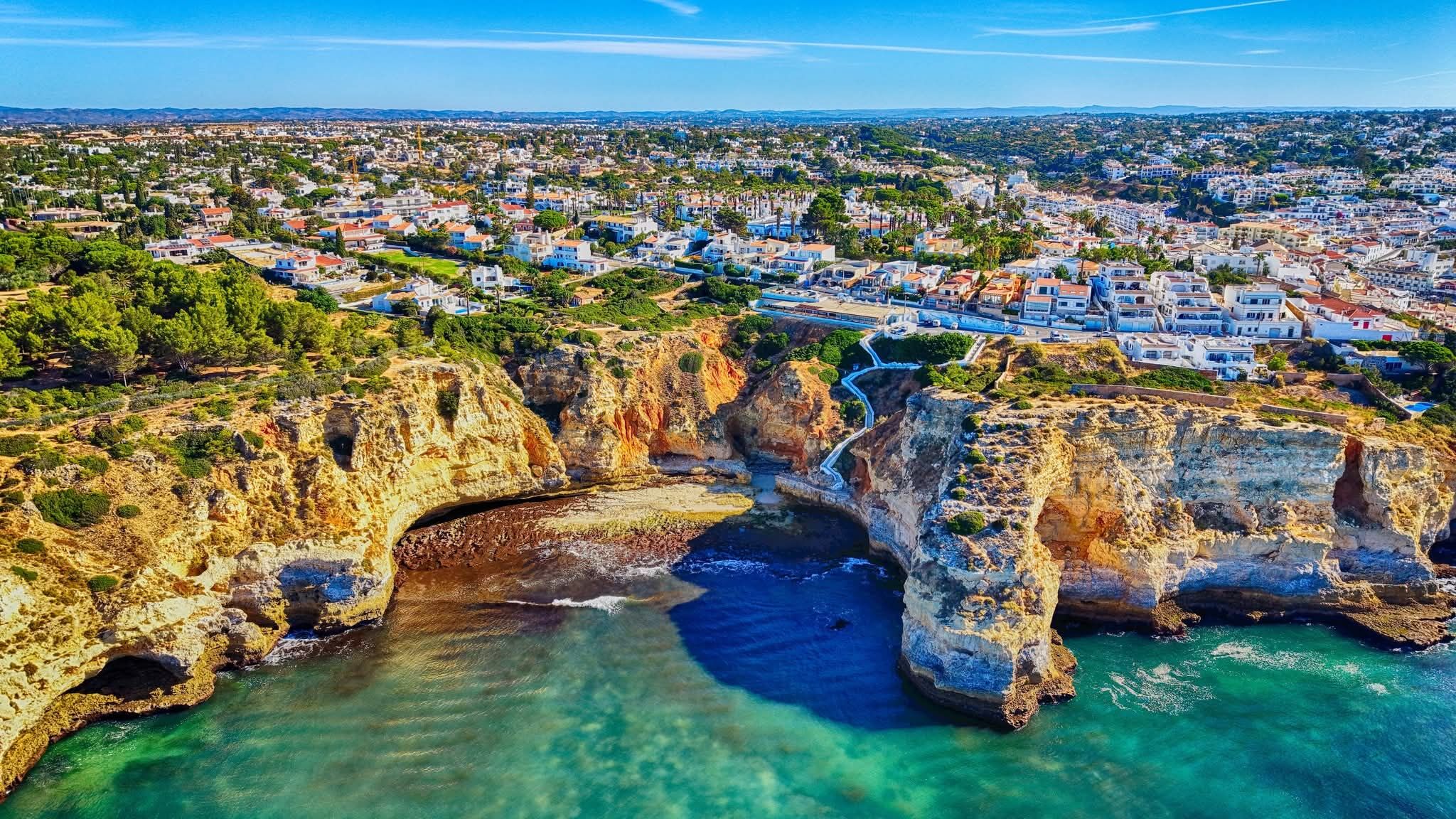 A secluded turquoise cove framed by golden cliffs near Carvoeiro