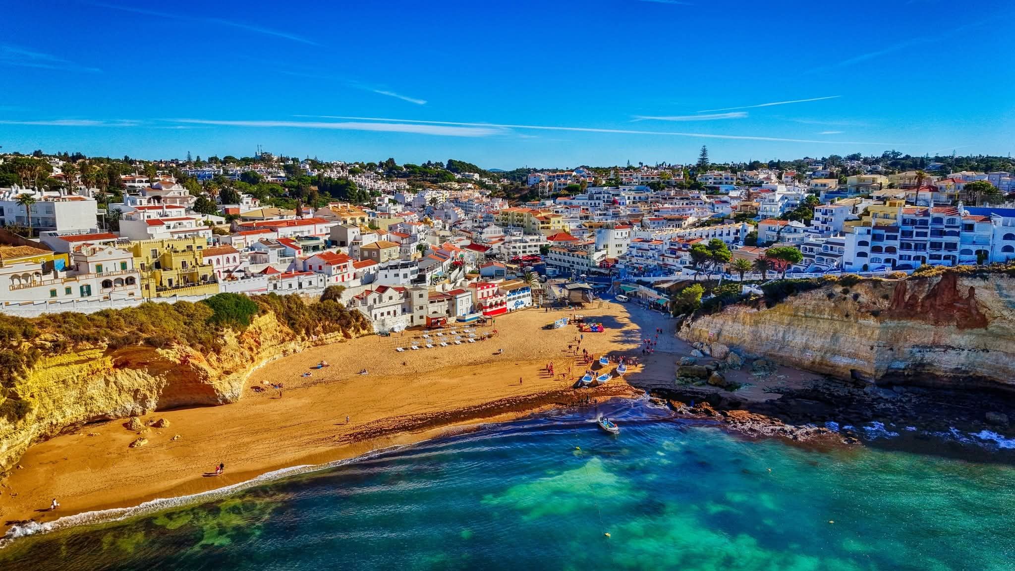 Carvoeiro's whitewashed houses curving around a golden cove and turquoise sea