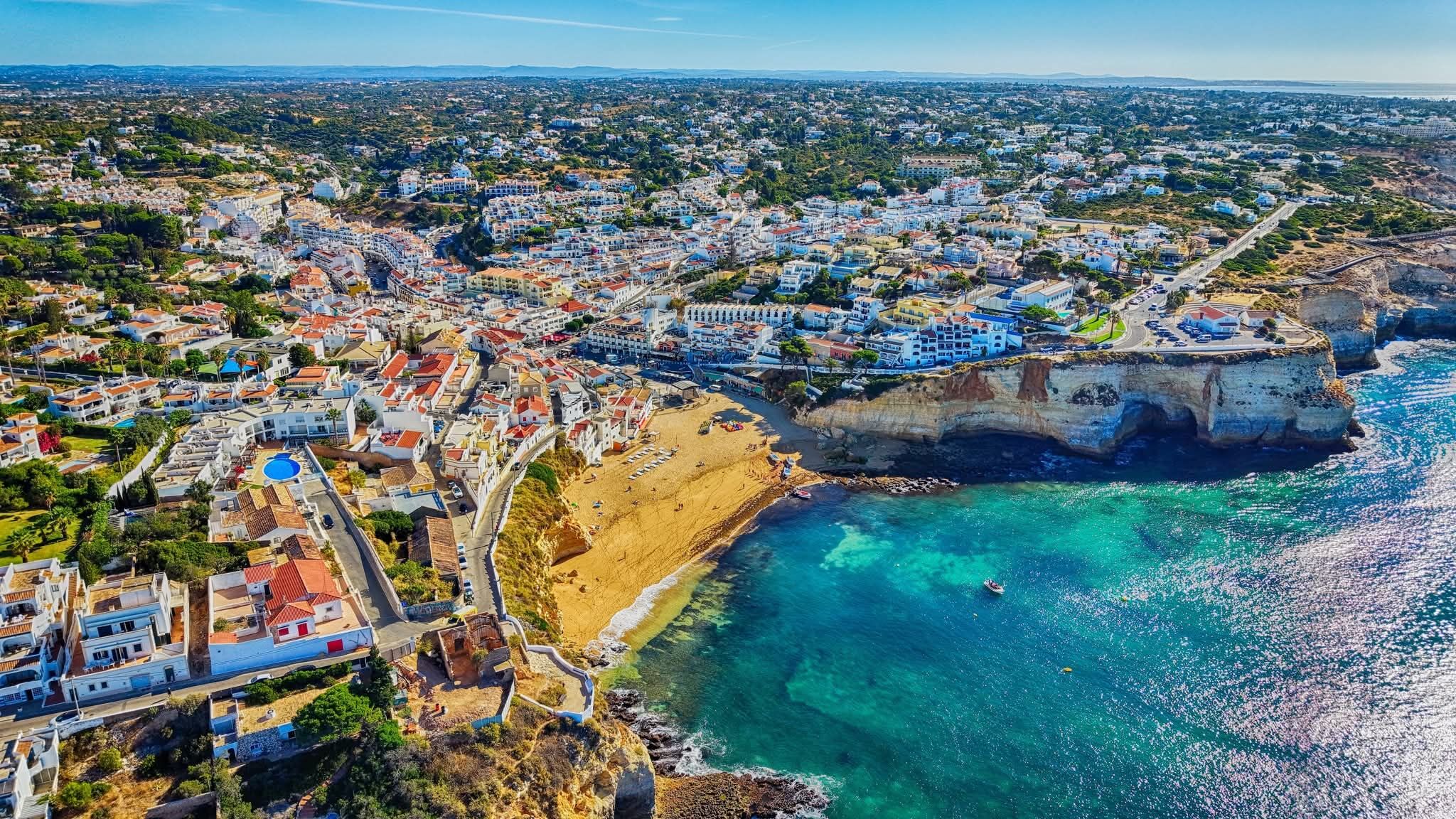 Aerial view of Carvoeiro's whitewashed village meeting its beach