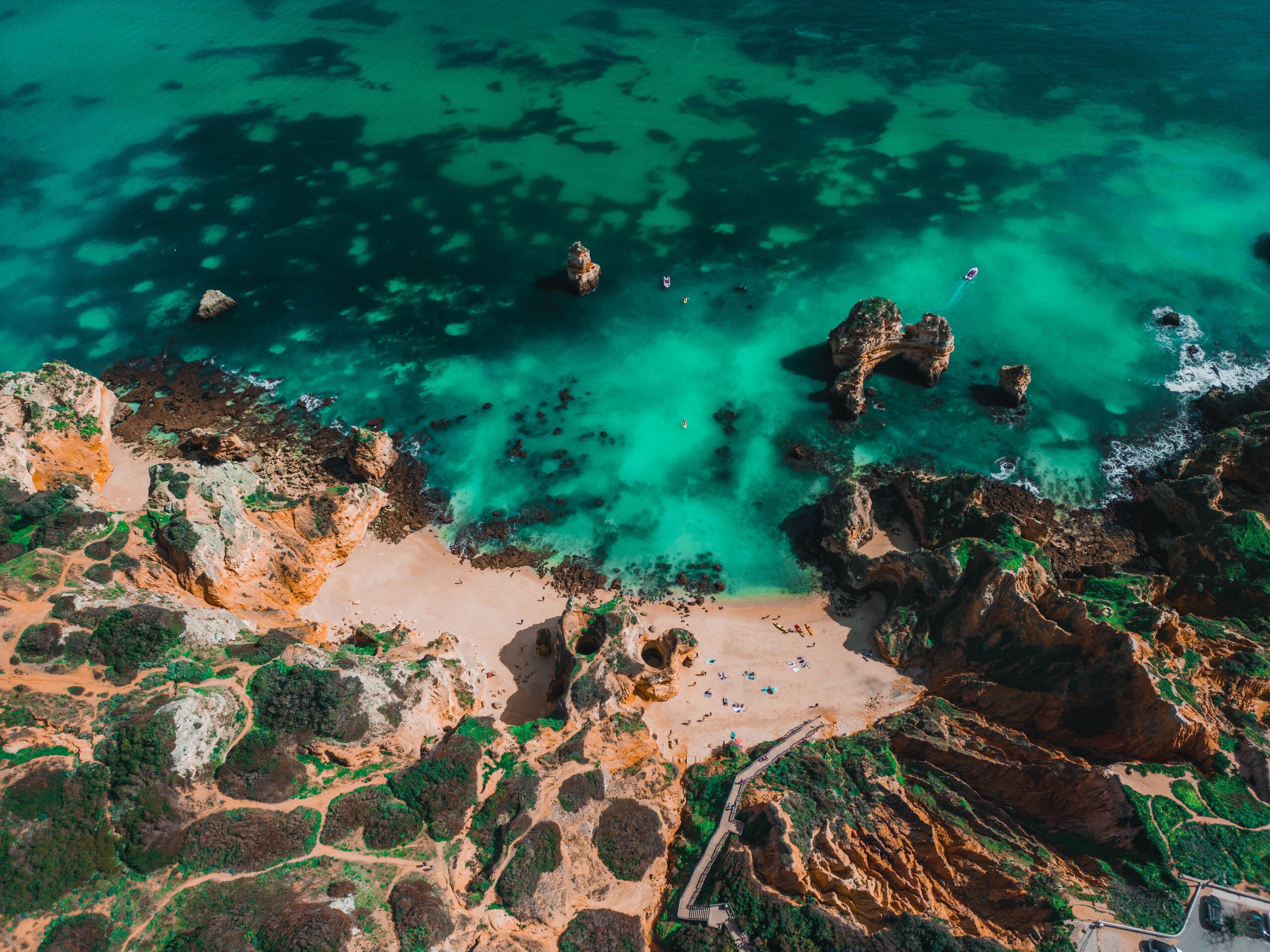 Top-down aerial of a hidden Lagos cove with turquoise water and ochre cliffs