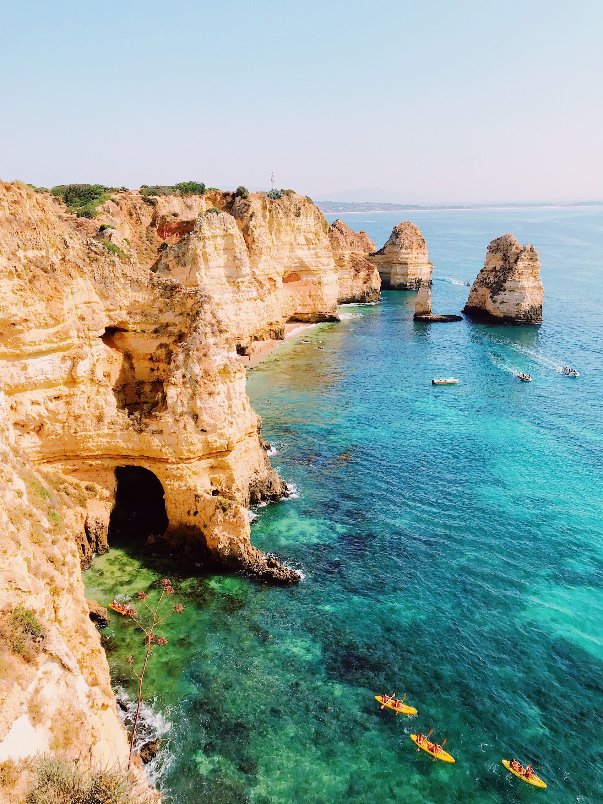 Kayakers gliding through turquoise water beneath the golden cliffs and grottoes of Ponta da Piedade